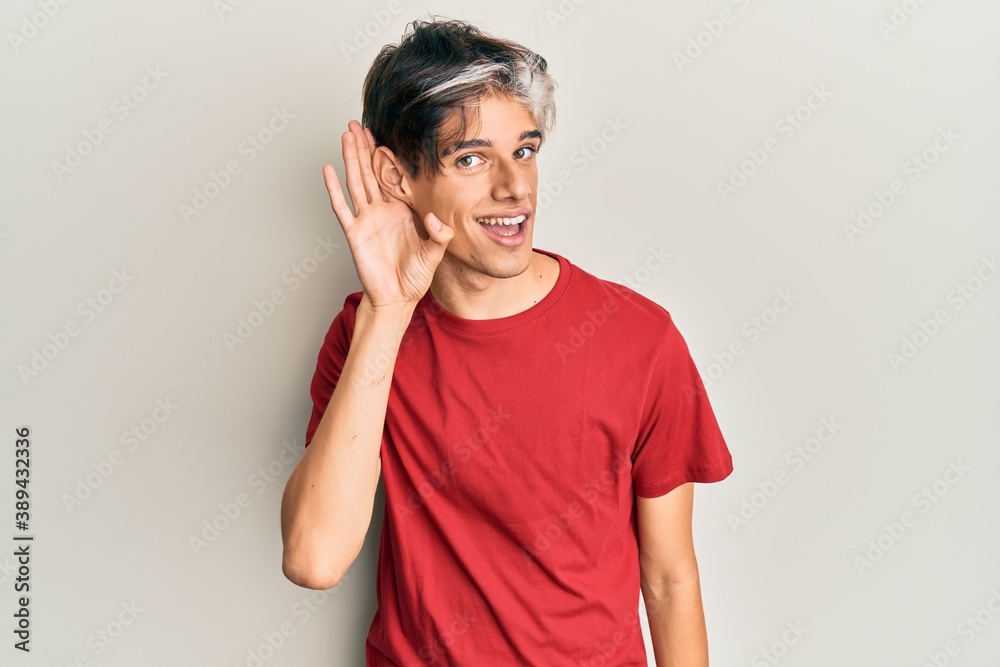 Young hispanic man wearing casual clothes smiling with hand over ear listening an hearing to rumor or gossip. deafness concept. Young hispanic man wearing casual clothes smiling with hand over ear listening an hearing to rumor or gossip. deafness concept.