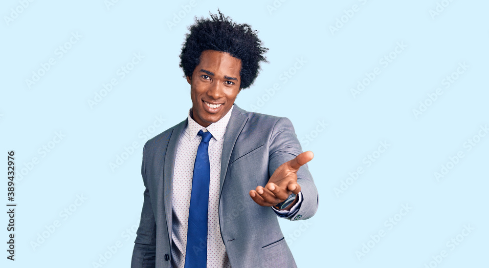 Handsome african american man with afro hair wearing business jacket smiling cheerful offering palm hand giving assistance and acceptance. Handsome african american man with afro hair wearing business jacket smiling cheerful offering palm hand giving assistance and acceptance.