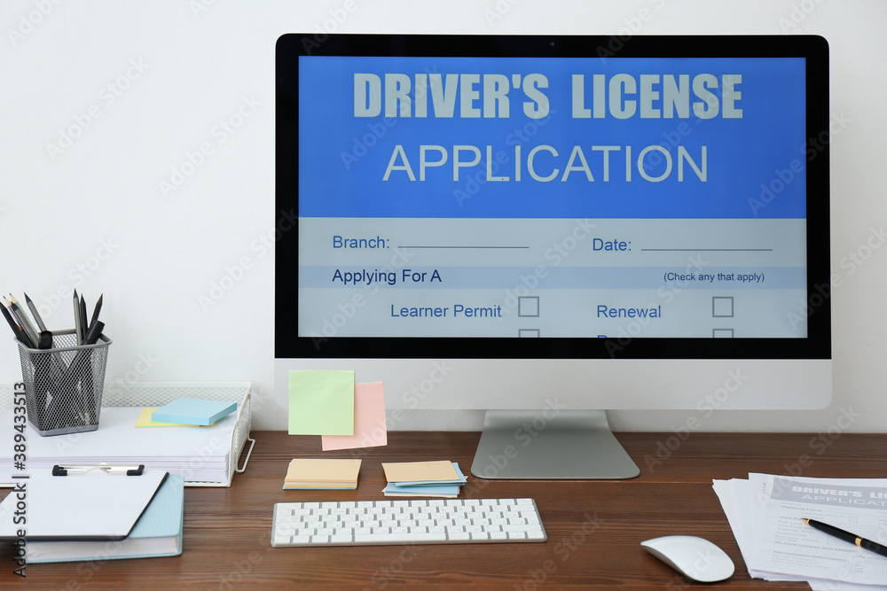 Computer with driver's license application form on table in office Computer with driver's license application form on table in office