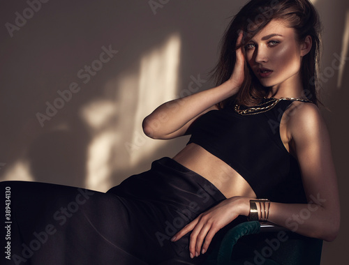 beautiful young woman in sexy black clothes. sitting Girl with a necklace on her neck