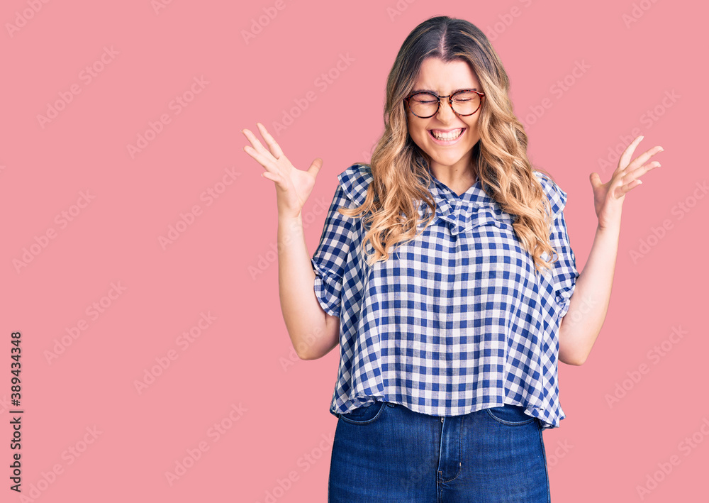 Young caucasian woman wearing casual clothes celebrating mad and crazy for success with arms raised and closed eyes screaming excited. winner concept Young caucasian woman wearing casual clothes celebrating mad and crazy for success with arms raised and closed eyes screaming excited. winner concept
