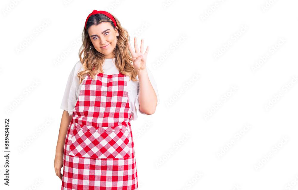 Young caucasian woman wearing apron showing and pointing up with fingers number four while smiling confident and happy. Young caucasian woman wearing apron showing and pointing up with fingers number four while smiling confident and happy.