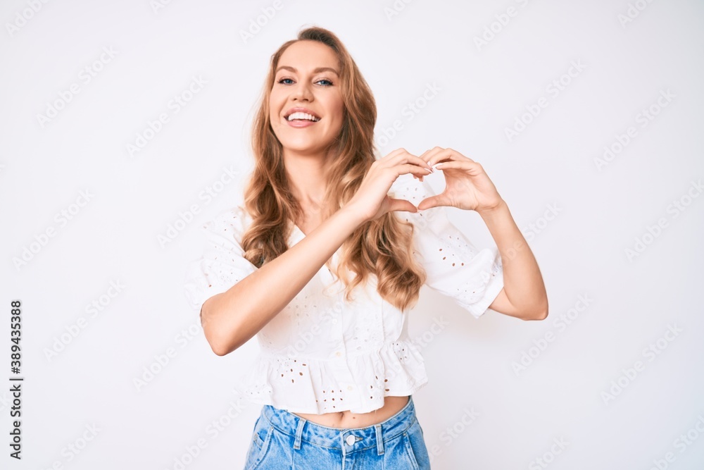 Young caucasian woman with blond hair wearing casual summer clothes smiling in love showing heart symbol and shape with hands. romantic concept. Young caucasian woman with blond hair wearing casual summer clothes smiling in love showing heart symbol and shape with hands. romantic concept.