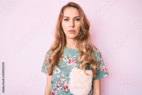 Young caucasian woman with blond hair wearing casual clothes with serious expression on face. simple and natural looking at the camera.