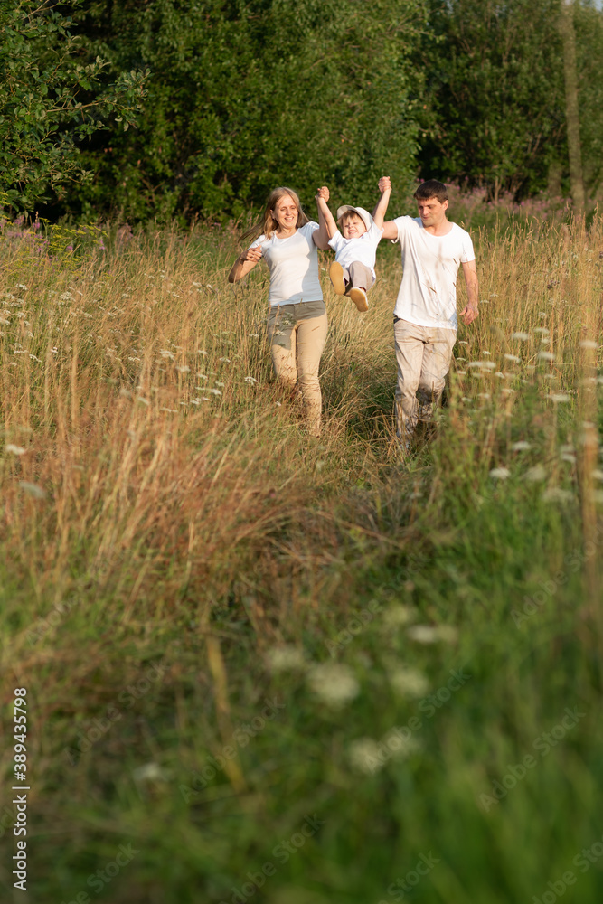 Happy family enjoying walk together at meadow in summer Happy family enjoying walk together at meadow in summer