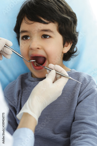 Little arab boy sitting at dental chair with open mouth during oral checking up with dentist doctor. Stomatology concept