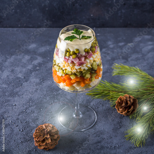 Traditional New Year Russian salad Winter or Olivie. Christmas food served in glass on dark background. Copy space for text, low key photo