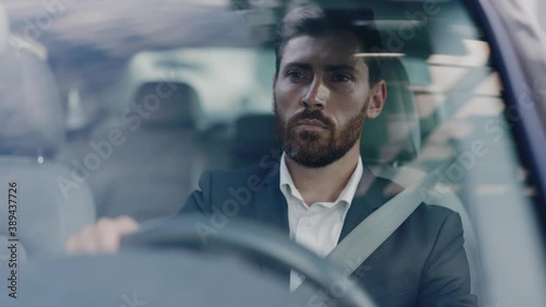 Concentrated caucasian adult handsome entrepreneur business person driving car rolling steering wheel traveling in city center. Destination. Business trip. Transport concept.