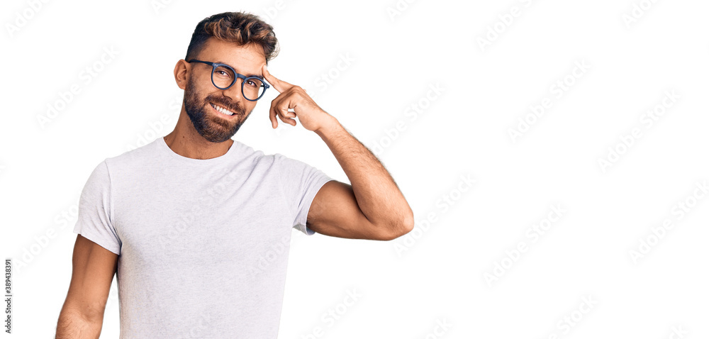 Young hispanic man wearing casual clothes and glasses smiling pointing to head with one finger, great idea or thought, good memory Young hispanic man wearing casual clothes and glasses smiling pointing to head with one finger, great idea or thought, good memory