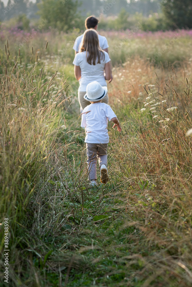 Happy family enjoying walk together at meadow in summer Happy family enjoying walk together at meadow in summer