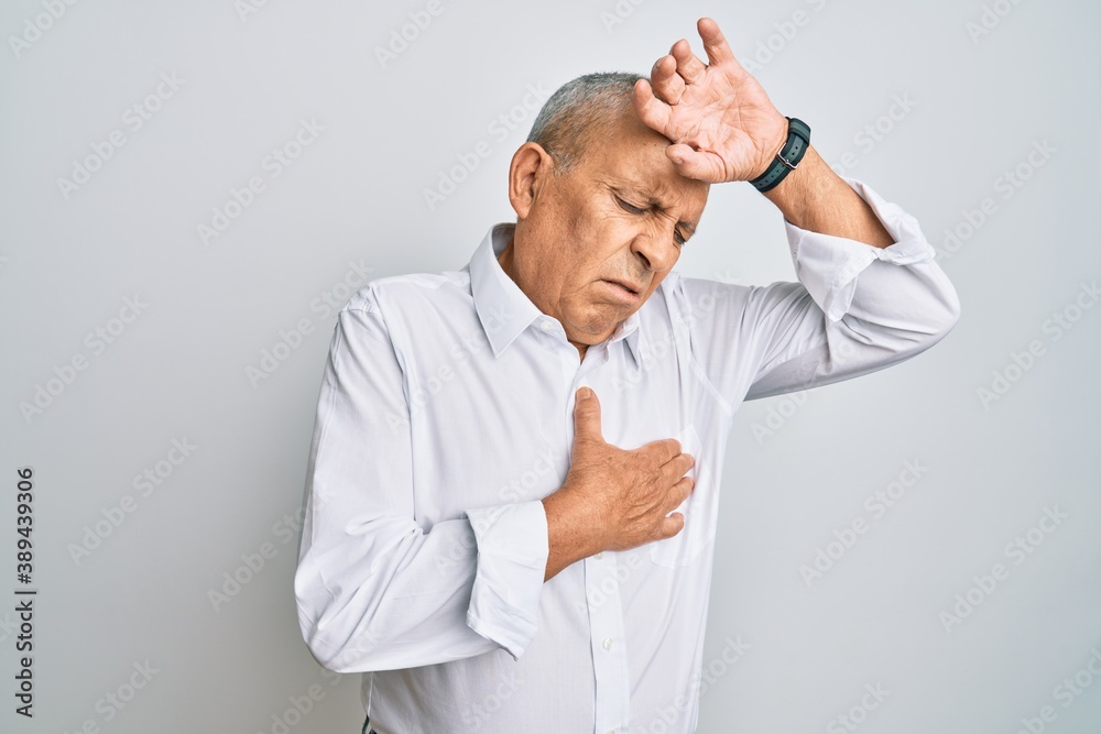 Handsome senior man wearing casual white shirt touching forehead for illness and fever, flu and cold, virus sick Handsome senior man wearing casual white shirt touching forehead for illness and fever, flu and cold, virus sick