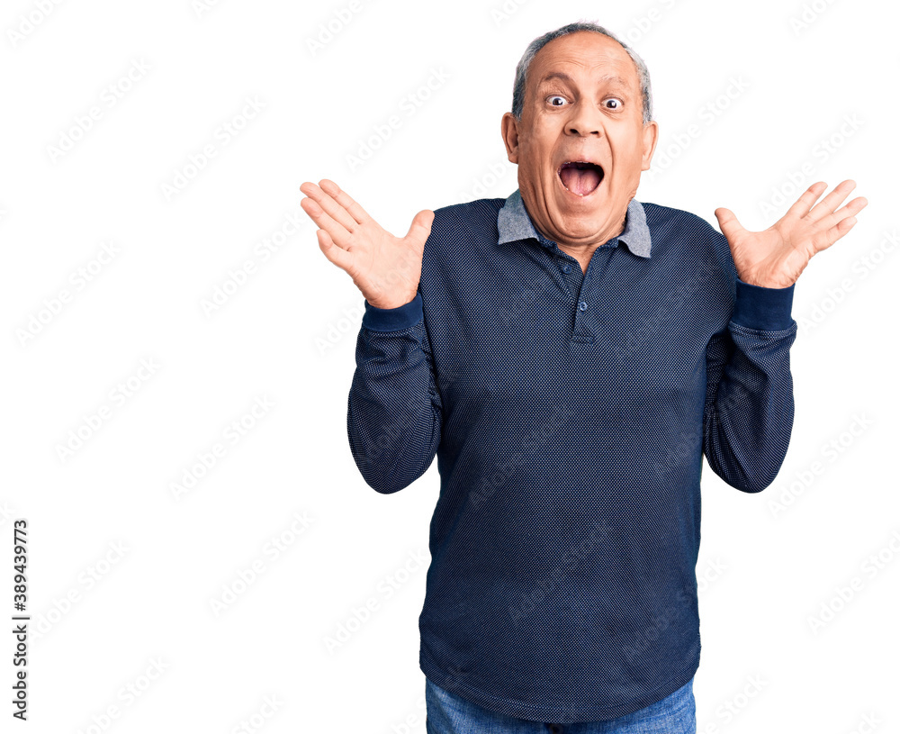 Naklejka premium Senior handsome man wearing casual polo celebrating crazy and amazed for success with arms raised and open eyes screaming excited. winner concept
