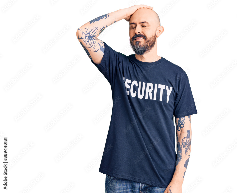 Young handsome man wearing security t shirt smiling confident touching hair with hand up gesture, posing attractive and fashionable Young handsome man wearing security t shirt smiling confident touching hair with hand up gesture, posing attractive and fashionable