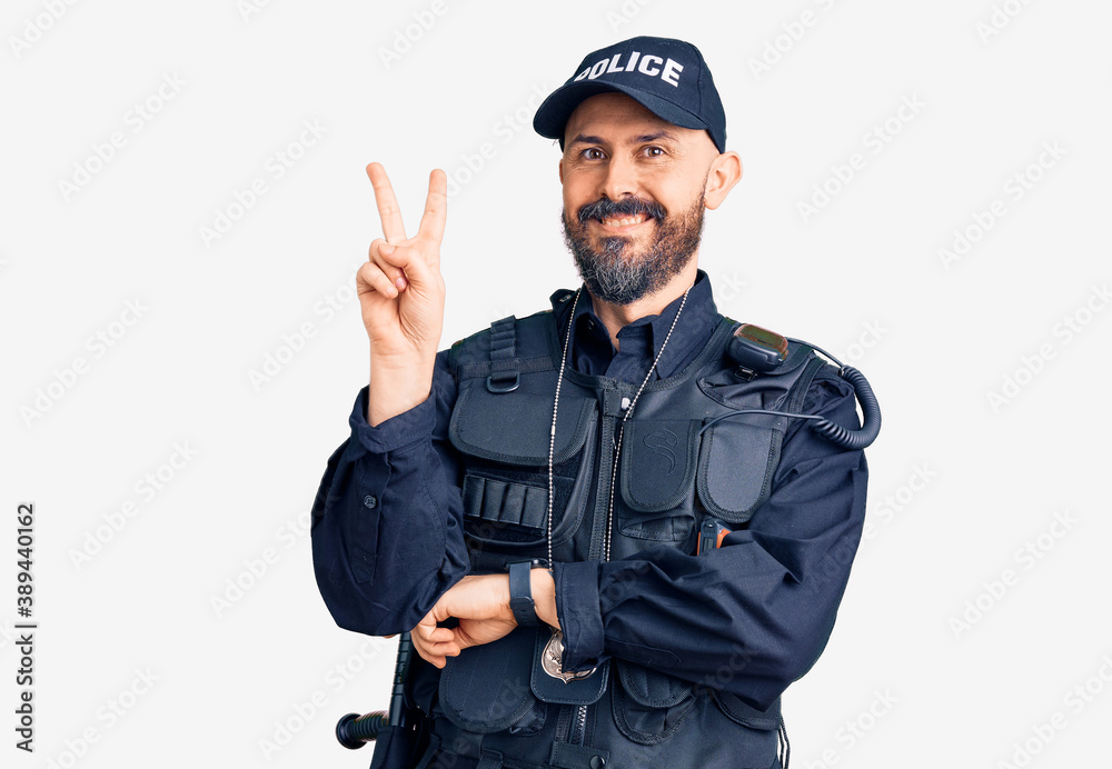 Young handsome man wearing police uniform smiling with happy face winking at the camera doing victory sign with fingers. number two. Young handsome man wearing police uniform smiling with happy face winking at the camera doing victory sign with fingers. number two.