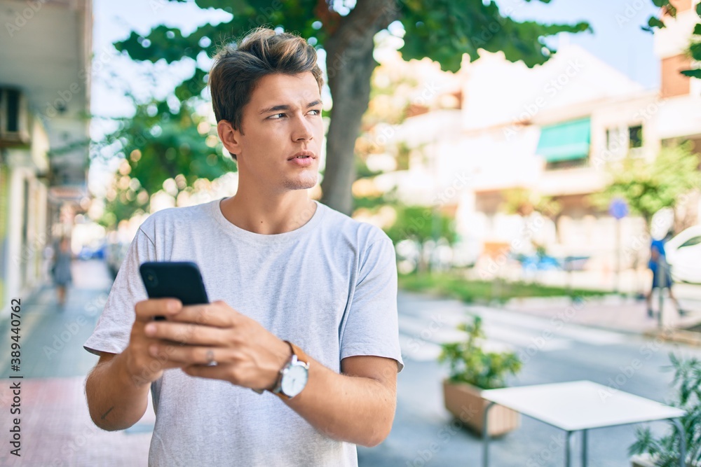 Young caucasian man with serious expression using smartphone at the city. Young caucasian man with serious expression using smartphone at the city.