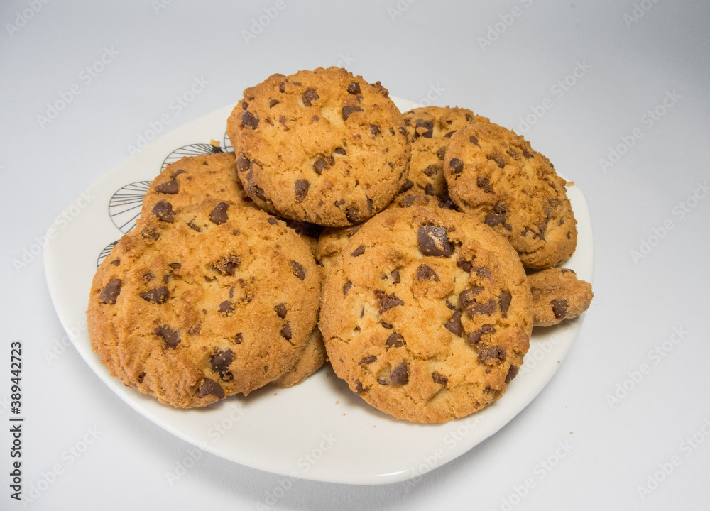 A closeup of freshly baked chocolate chip cookies on a saucer isolated on white background
