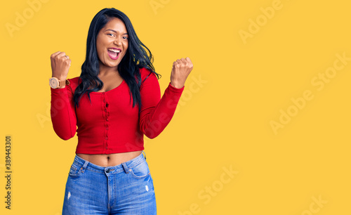 Hispanic woman with long hair wearing casual clothes screaming proud, celebrating victory and success very excited with raised arms