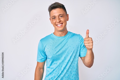 Young hispanic boy wearing casual clothes smiling happy and positive, thumb up doing excellent and approval sign