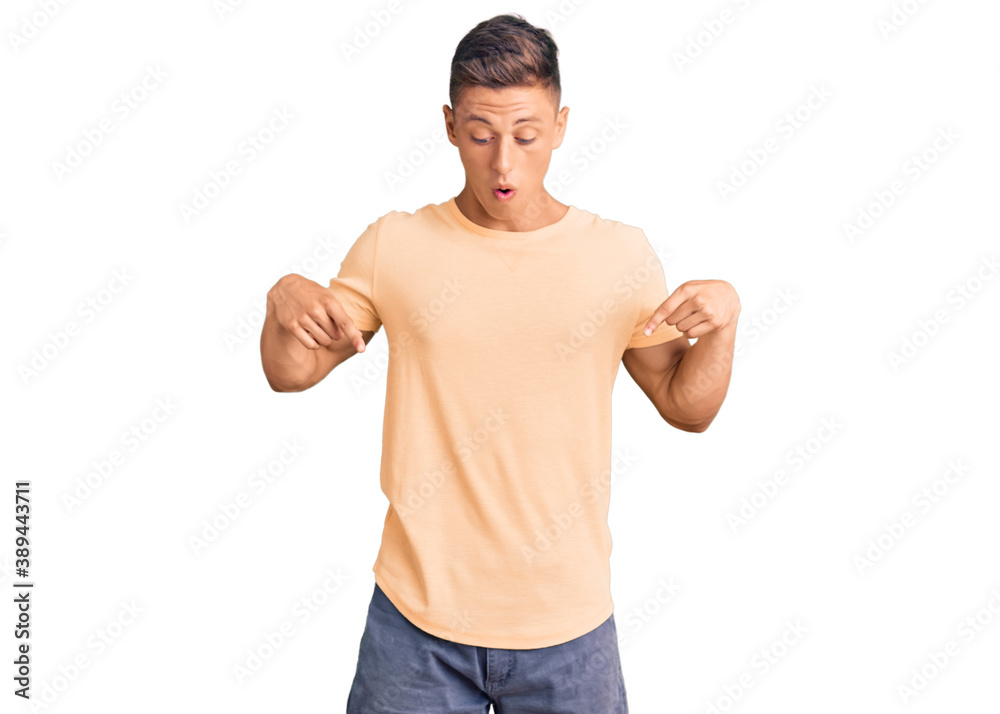 Young handsome man wearing casual clothes pointing down with fingers showing advertisement, surprised face and open mouth Young handsome man wearing casual clothes pointing down with fingers showing advertisement, surprised face and open mouth