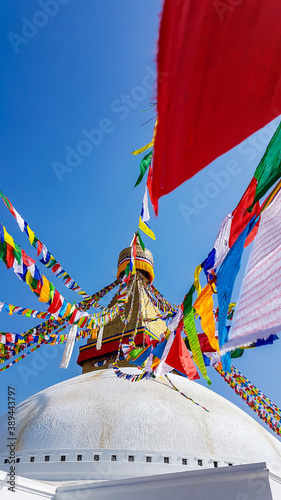 The Bouddhanath Temple in Kathmandu, Nepal. The temple has many colourful prayer flags with 'om mani padme hum' mantra written on them attached to it's golden rooftop. Spirituality and meditation.