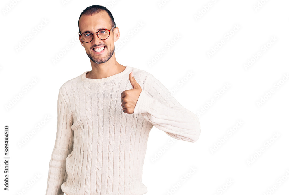 Young handsome man wearing casual clothes and glasses doing happy thumbs up gesture with hand. approving expression looking at the camera showing success.