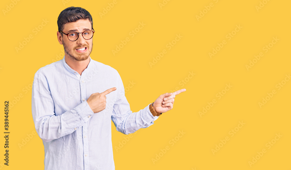 Handsome young man with bear wearing elegant business shirt and glasses pointing aside worried and nervous with both hands, concerned and surprised expression Handsome young man with bear wearing elegant business shirt and glasses pointing aside worried and nervous with both hands, concerned and surprised expression