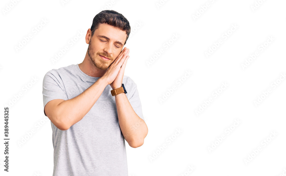 Handsome young man with bear wearing casual tshirt sleeping tired dreaming and posing with hands together while smiling with closed eyes. Handsome young man with bear wearing casual tshirt sleeping tired dreaming and posing with hands together while smiling with closed eyes.