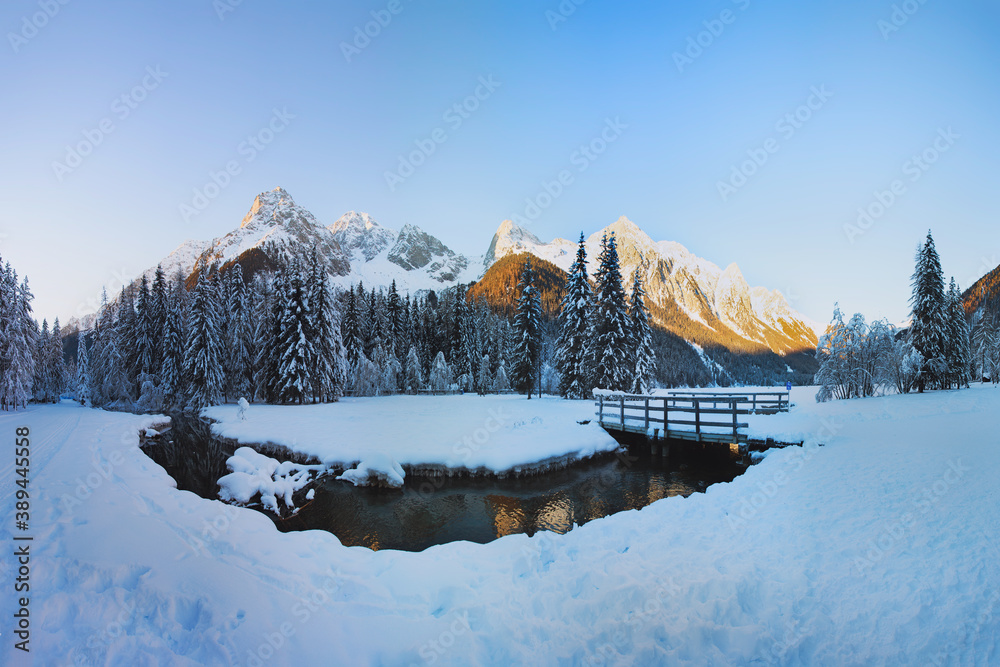 Winter landscape in the Alps, Christmas card view. Lake Antholz (Anterselva) at sunset, Dolomites, Italy. The river against the background of snow-covered peaks.