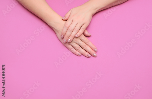 Women's hands with a beautiful delicate manicure on a colored background. View from above. A place for text.