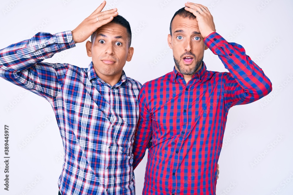 Naklejka premium Young gay couple of two men wearing casual clothes surprised with hand on head for mistake, remember error. forgot, bad memory concept.
