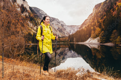 Woman with backpack and raincoat hiking Lifestyle adventure concept forest and lake on background active vacations into the wild photo