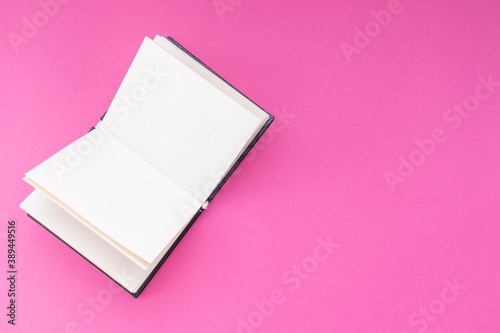 Open paper book with blank pages on pink background. With copy space.