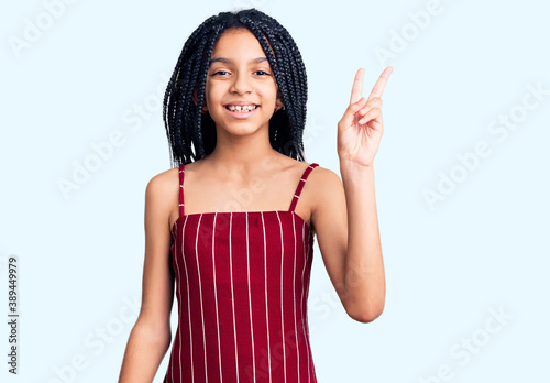 Cute african american girl wearing casual clothes smiling with happy face winking at the camera doing victory sign. number two.