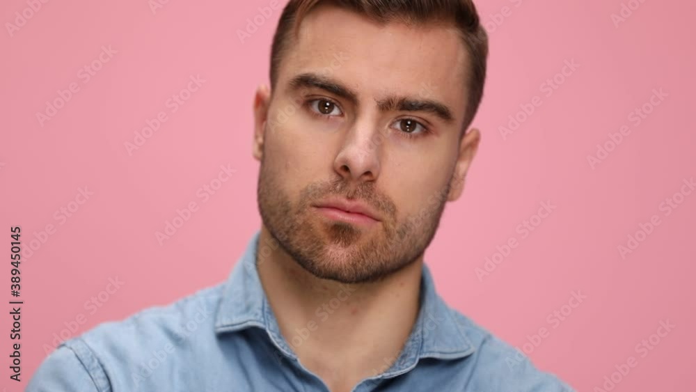 sexy casual young man in blue shirt looking down, moving head and posing, standing on pink background in studio sexy casual young man in blue shirt looking down, moving head and posing, standing on pink background in studio