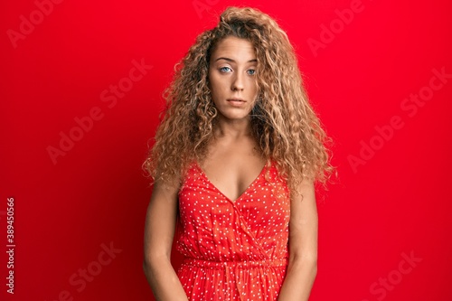 Beautiful caucasian teenager girl wearing summer dress with serious expression on face. simple and natural looking at the camera.