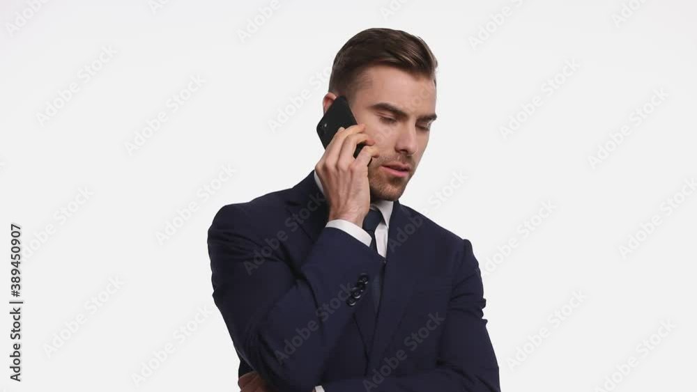 sexy young businessman in navy blue suit talking on the phone, smiling and pointing fingers, standing isolated on white background in studio sexy young businessman in navy blue suit talking on the phone, smiling and pointing fingers, standing isolated on white background in studio