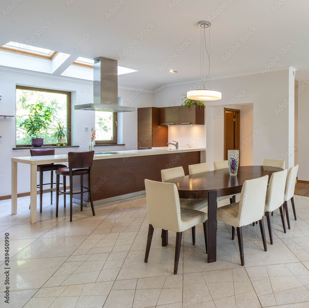 Modern interior of spacious luxury studio apartment. Wooden table and chairs. Kitchen set. Modern interior of spacious luxury studio apartment. Wooden table and chairs. Kitchen set.