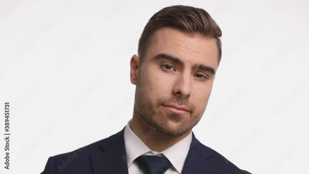 confident young businessman in navy blue suit fixing tie, sensually touching chin and beard and thinking, crossing arms and posing on white background in studio confident young businessman in navy blue suit fixing tie, sensually touching chin and beard and thinking, crossing arms and posing on white background in studio