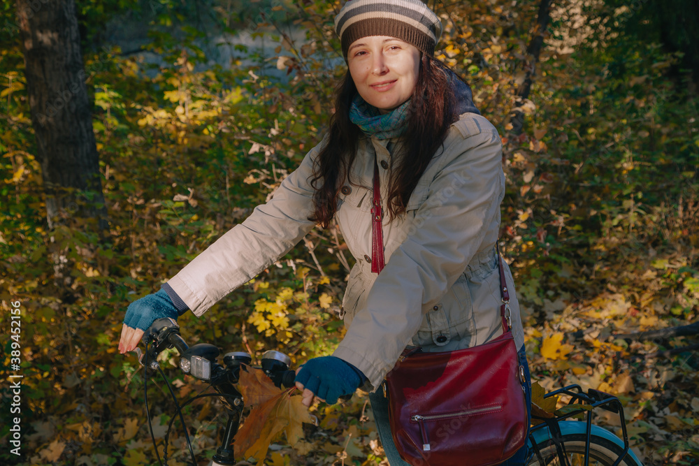 Pretty brunette leans on bicycle in autumn park Pretty brunette leans on bicycle in autumn park