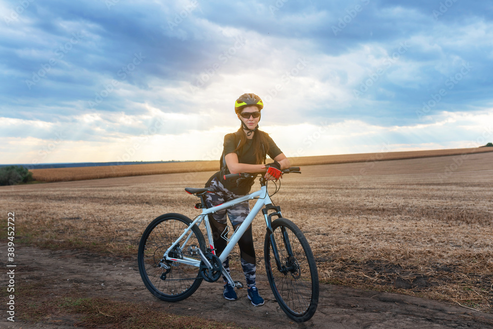 smiling girl standing with a bicycle in the middle of the evening field smiling girl standing with a bicycle in the middle of the evening field