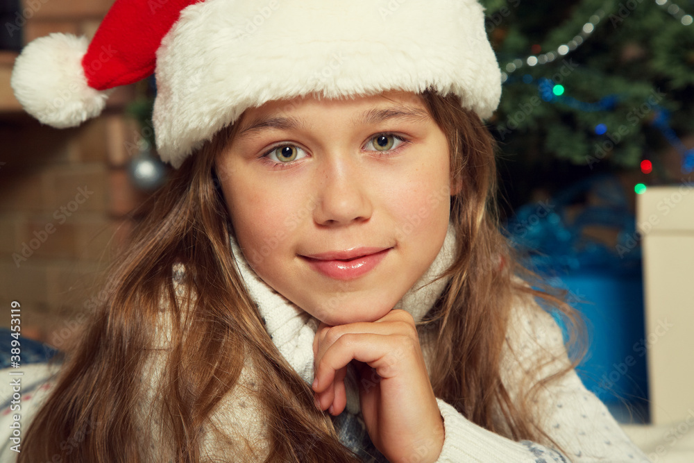 Cute teenage girl in santa hat near Christmas tree. xmas kid. Cute teenage girl in santa hat near Christmas tree. xmas kid.