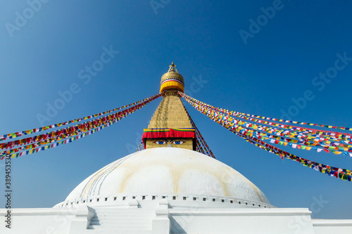 The Bouddhanath Temple in Kathmandu  Nepal. The temple has many colourful prayer flags with  om mani padme hum  mantra written on them attached to it s golden rooftop. Spirituality and meditation.