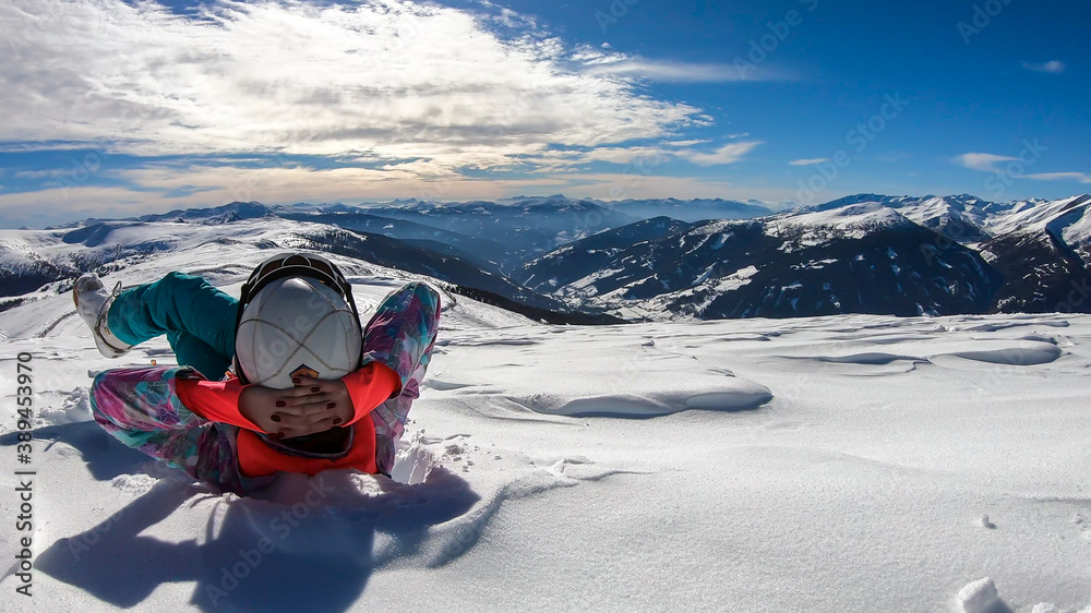 A woman lying in powder snow any enjoying the sun on top of Katschberg in Austria. She is happy and joyful. Panoramic view on the surrounding mountains. Winter wonderland, Clear and sunny winter day A woman lying in powder snow any enjoying the sun on top of Katschberg in Austria. She is happy and joyful. Panoramic view on the surrounding mountains. Winter wonderland, Clear and sunny winter day