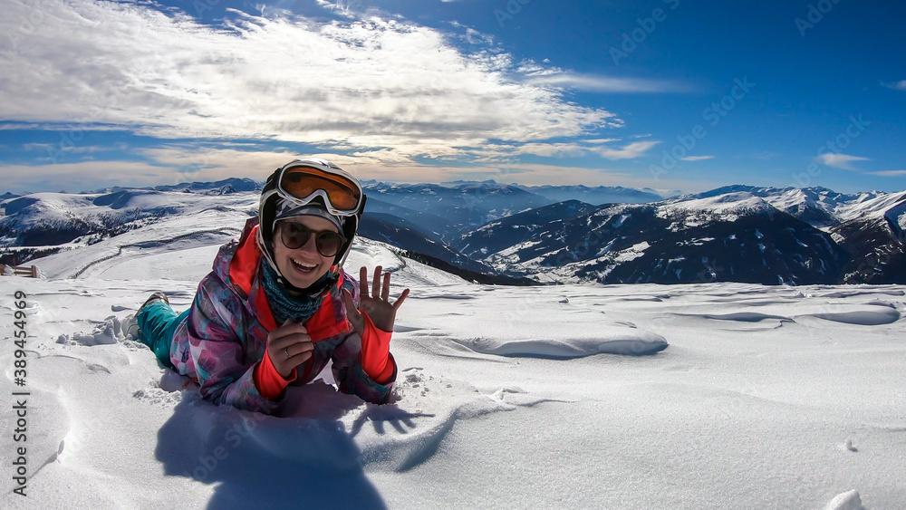 A woman lying in powder snow any enjoying the sun on top of Katschberg in Austria. She is happy and joyful. Panoramic view on the surrounding mountains. Winter wonderland, Clear and sunny winter day A woman lying in powder snow any enjoying the sun on top of Katschberg in Austria. She is happy and joyful. Panoramic view on the surrounding mountains. Winter wonderland, Clear and sunny winter day