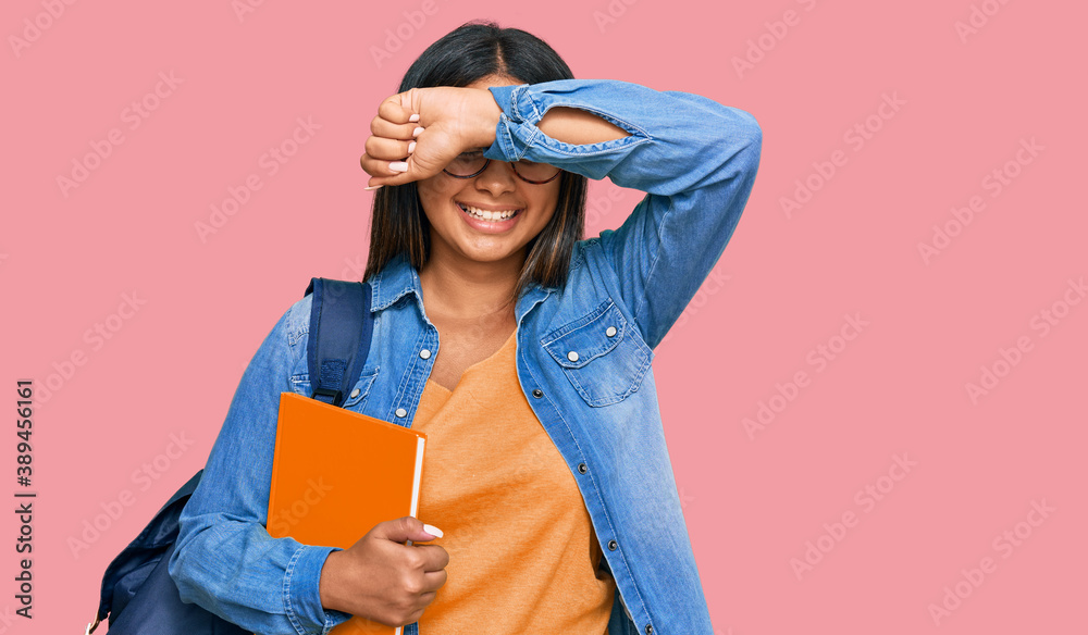 Young latin girl wearing student backpack and holding books smiling cheerful playing peek a boo with hands showing face. surprised and exited Young latin girl wearing student backpack and holding books smiling cheerful playing peek a boo with hands showing face. surprised and exited