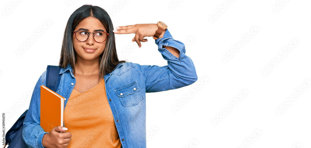 Young latin girl wearing student backpack and holding books shooting and killing oneself pointing hand and fingers to head like gun, suicide gesture. Young latin girl wearing student backpack and holding books shooting and killing oneself pointing hand and fingers to head like gun, suicide gesture.