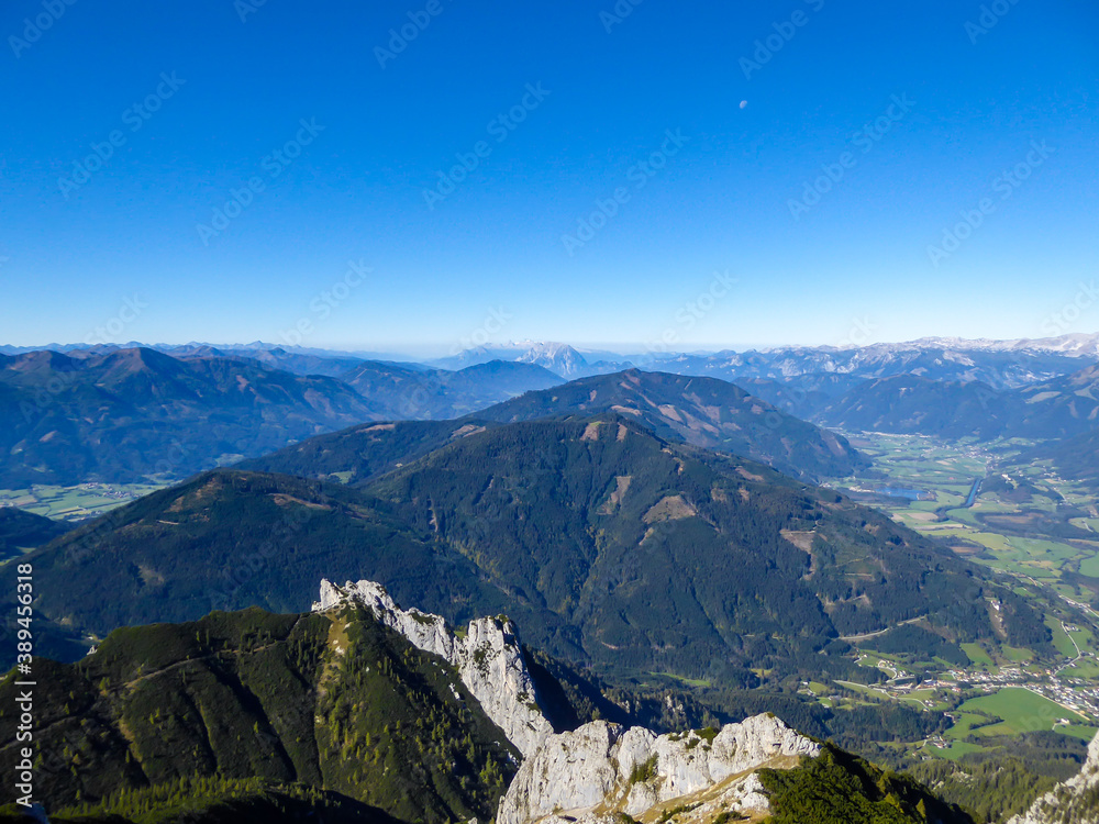 Panoramic view on a massive mountain chains in Kaiserau Kreuzkogel region, Austrian Alps. The steep slopes are overgrown with grass. Sharp peaks. Dangerous mountaineering. Sunny summer day. Adventure