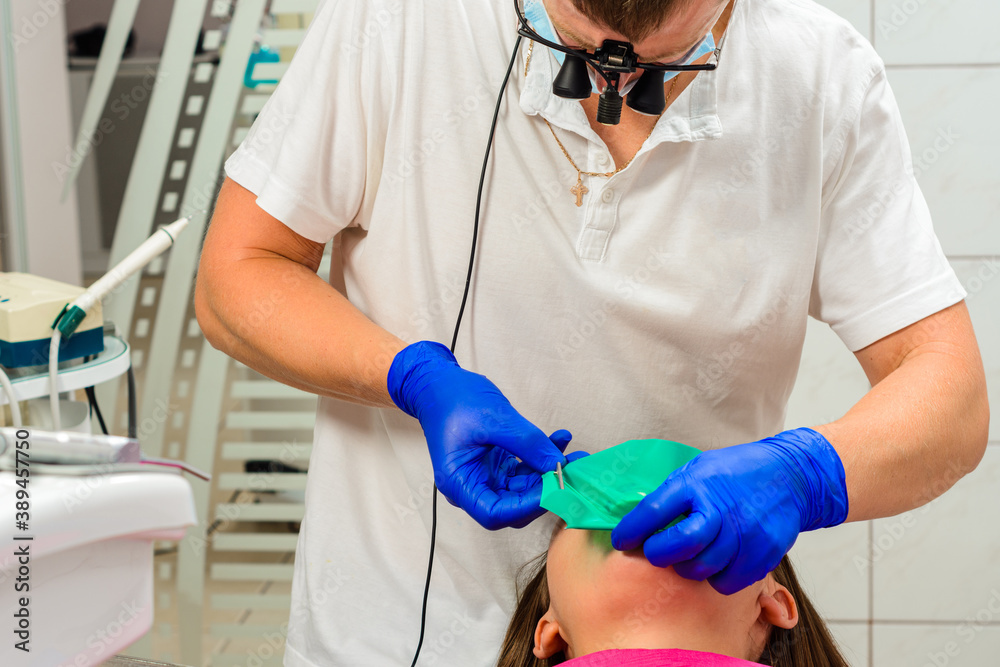 Installation of a rubber dam with a metal clamp for dental fillings