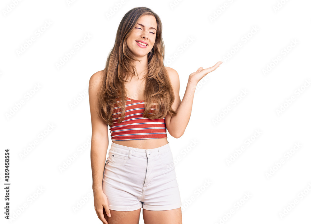 Beautiful caucasian young woman wearing casual clothes smiling cheerful presenting and pointing with palm of hand looking at the camera. Beautiful caucasian young woman wearing casual clothes smiling cheerful presenting and pointing with palm of hand looking at the camera.