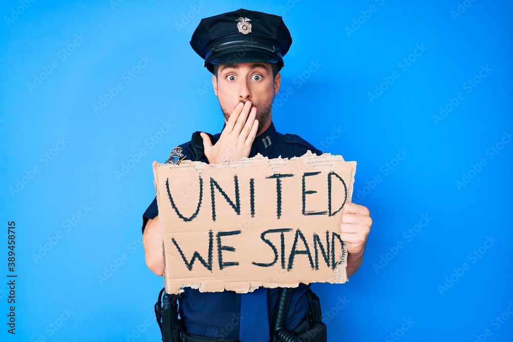 Young caucasian man wearing police uniform holding united we stand banner covering mouth with hand, shocked and afraid for mistake. surprised expression Young caucasian man wearing police uniform holding united we stand banner covering mouth with hand, shocked and afraid for mistake. surprised expression